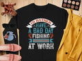 A flat lay features a Garment Graphics black unisex fishing sweatshirt with the quote, Id rather have a bad day fishing than a good day at work. Accompanied by a yellow jacket, blush pink shoes, sunglasses, makeup brushes and palette, plus a small blue pouch. Ideal for fishing enthusiasts.