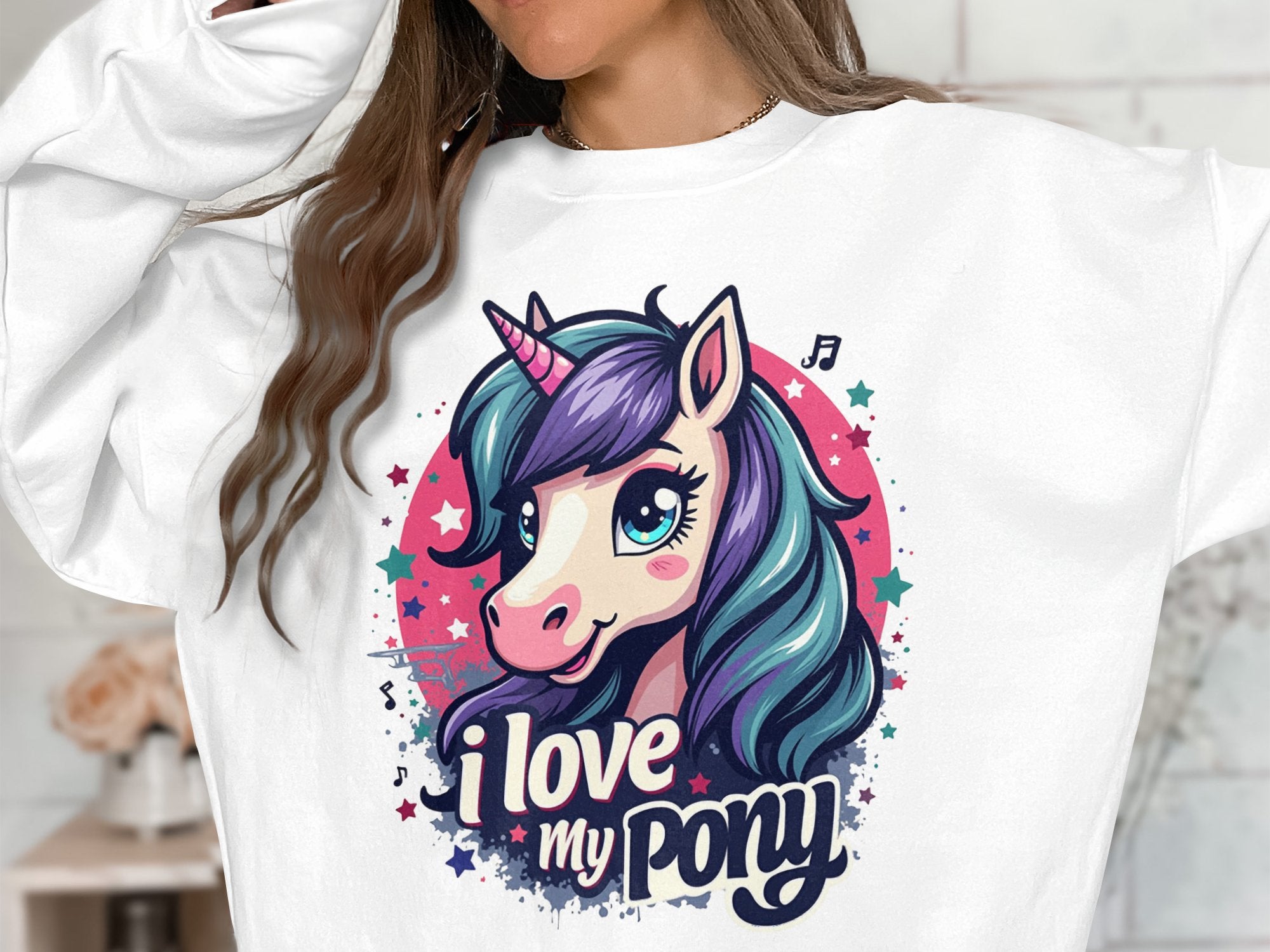 Sporting a lively graphic sweatshirt, someone displays a cartoon unicorn with purple and teal hair, encircled by colorful stars and musical notes. The Garment Graphics sweatshirt reads I love my ponyunicorn.