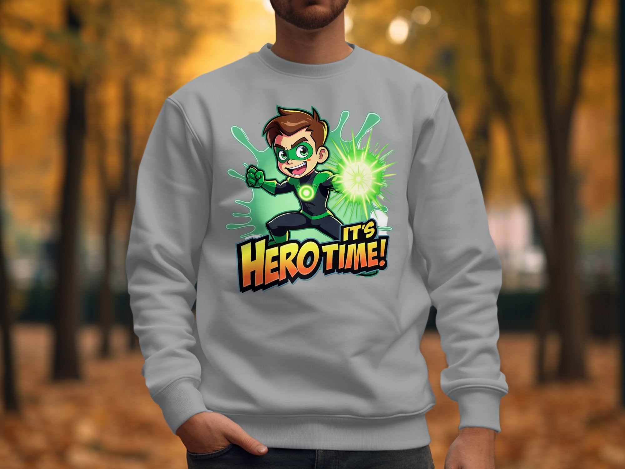 A vibrant youth wears a colorful Garment Graphics sweatshirt with an Its Herotime cartoon graphic, surrounded by vivid green energy. The parks blurred backdrop of autumn leaves beautifully complements their daring style.