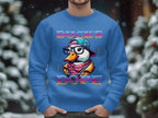 A person wears a blue Garment Graphics sweatshirt with a colorful duck in a cap, glasses, and bandana. It reads Ducks Dope against blurred snow-covered trees. Designed with medium-heavy fabric and unisex sizing for maximum comfort.