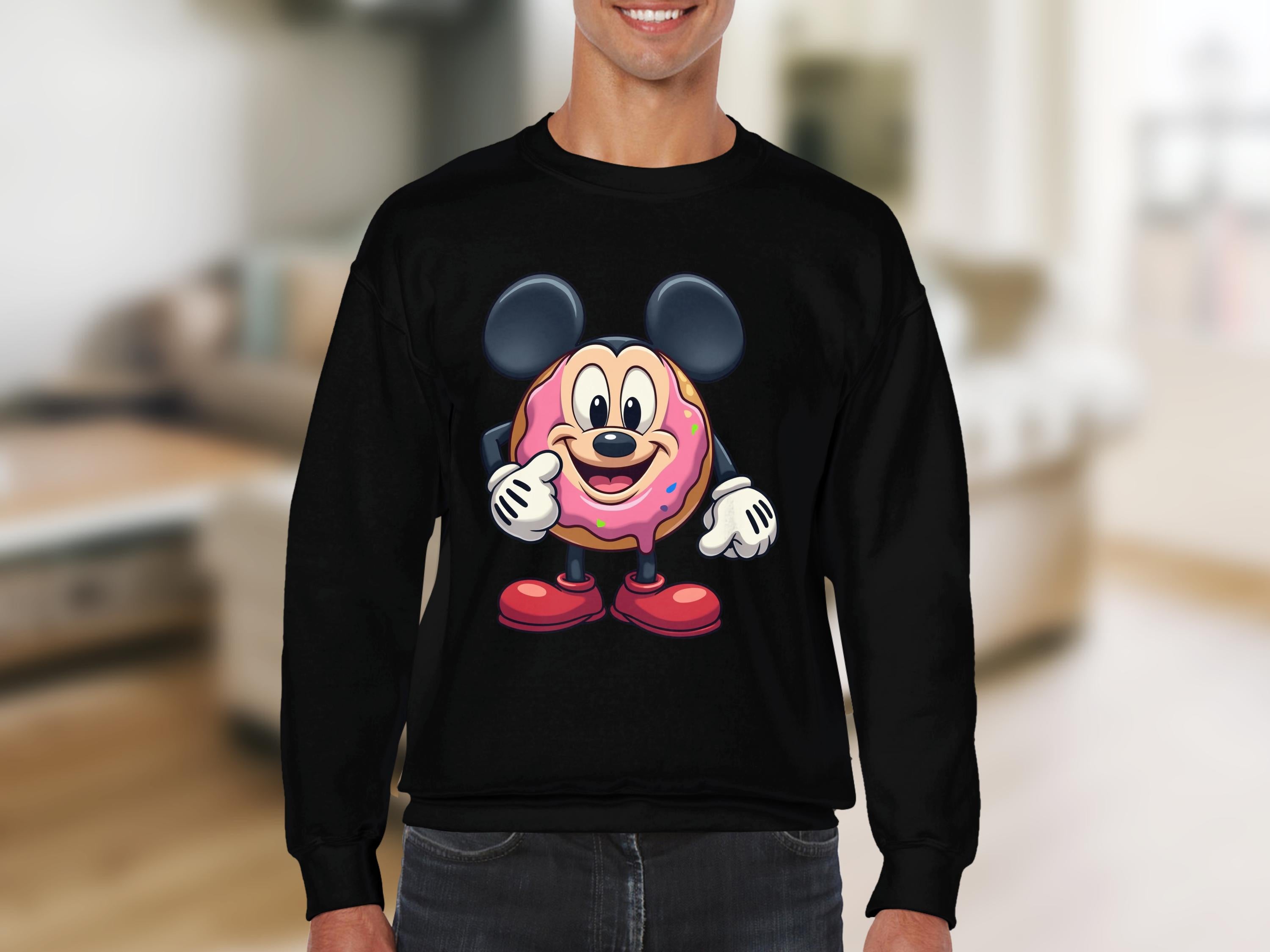Someone is wearing a quirky Garment Graphics sweatshirt featuring a cute cartoon donut character with big ears, red shoes, and gloves against a blurred indoor backdrop.