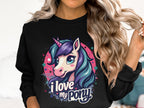 A person with long, wavy hair wears a Garment Graphics black sweatshirt showcasing a vibrant cartoon pony-unicorn with a blue-purple mane. The text I love my pony, surrounded by pink and turquoise stars, enhances its whimsical charm.