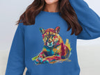 Someone in a blue sweatshirt from Garment Graphics, featuring a vibrant lounging cougar design, adjusts their hair with their face unseen.