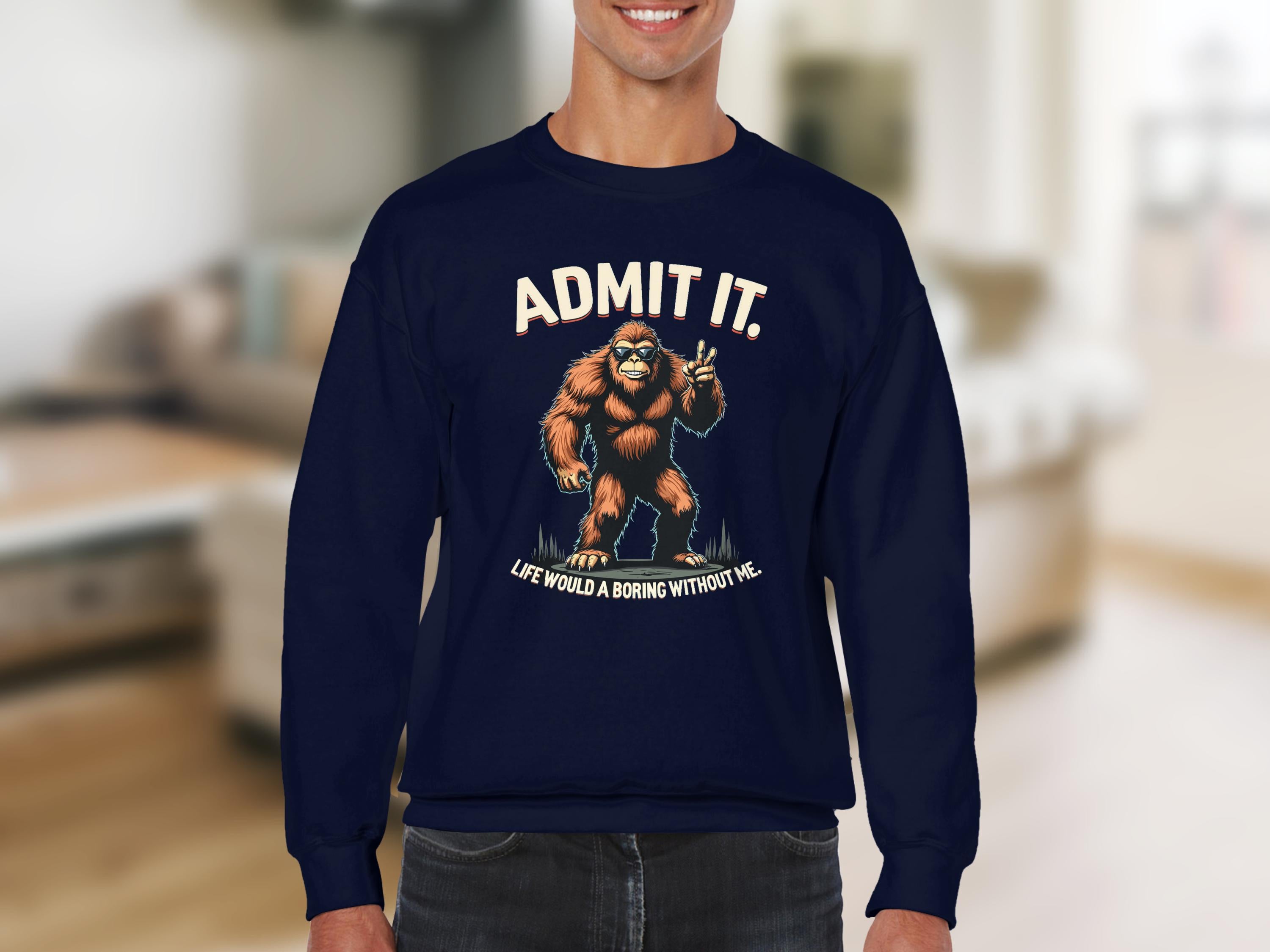 Garment Graphics presents a navy blue unisex sweatshirt with Bigfoot giving a thumbs-up and the humorous text, Admit it! Life would be boring without me, set against a blurred indoor backdrop for fans of casual wear.