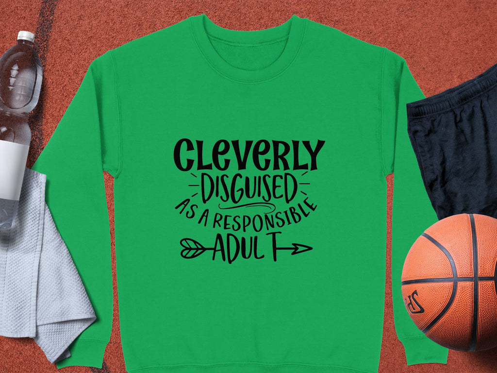This green sweatshirt by Garment Graphics, from the responsible adult collection, humorously states Cleverly disguised as a responsible adult in black. Its styled with essentials like a towel, water bottle, black shorts, and an orange basketball—perfect for any humor wardrobe.
