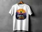 A white Garment Graphics t-shirt hangs on a wooden hanger, featuring a vibrant sunset with a hiker silhouette and bold text: Retired 2025 - Not My Problem Anymore, embodying the spirit of carefree retirement.