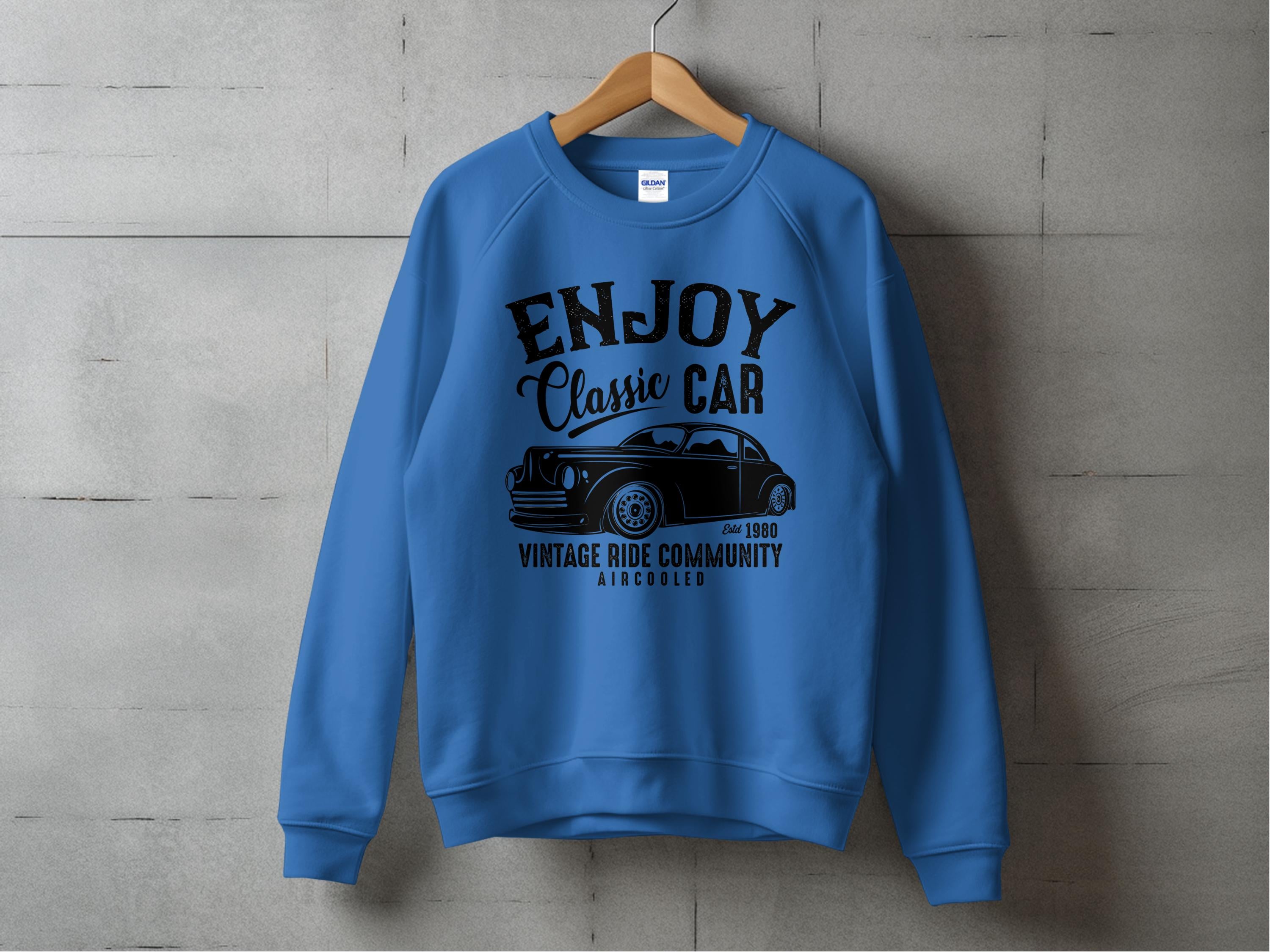 Garment Graphics presents a blue vintage ride sweatshirt featuring ENJOY Classic Car, Vintage Ride Community, Aircooled text and classic car illustration, set against a gray concrete wall background.