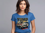 A dark-haired woman wears a blue t-shirt featuring a bold vintage racing car graphic and YUMP lettering by Garment Graphics, set against a plain gray background.