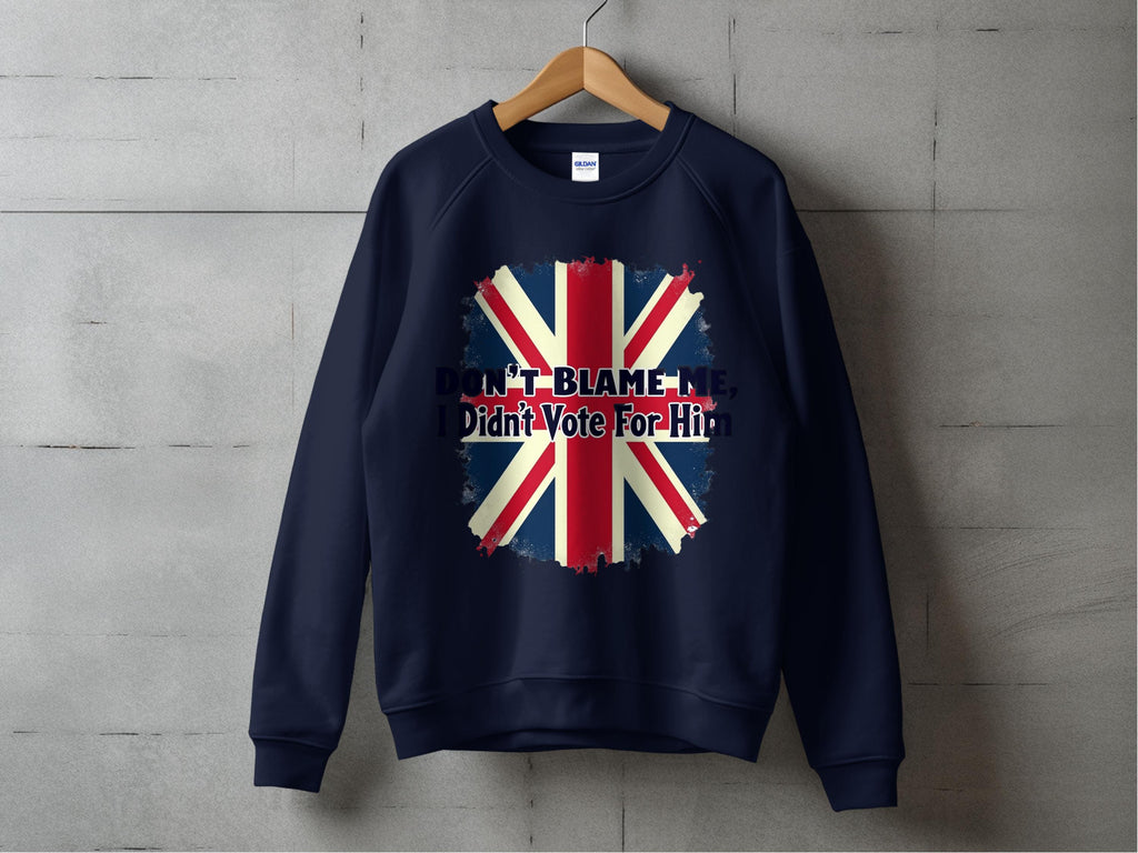 A Garment Graphics navy blue sweatshirt hangs against a grey wall, featuring a bold design with a distressed Union Jack and the phrase Dont blame me, I didnt vote for him in striking letters.