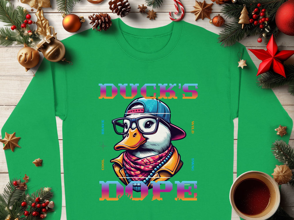 Presenting the Garment Graphics Sweatshirt: a medium-heavy green sweatshirt showcasing a cartoon duck with glasses, a backward cap, and scarf. The text says DUCKS DOPE. Nestled with holiday decor and hot drinks on wood, it offers unisex sizing.