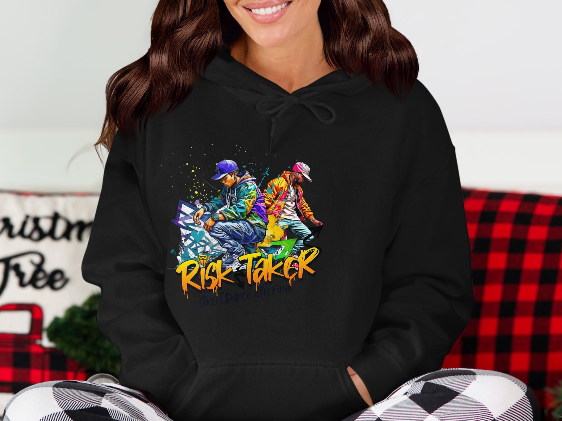 A person wears a Garment Graphics hoodie with two skaters in vibrant outfits. The striking yellow and orange Risk Taker lettering stands out against a red and black checkered backdrop, perfect for expressing Risk Taker Street Dance vibes.