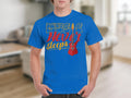 Someone is wearing a Garment Graphics T-shirt in blue, made of 100% cotton, featuring the phrase Music Never Sleeps alongside a red guitar graphic. The background shows a blurred interior with a couch and shelves, creating a cozy ambiance.