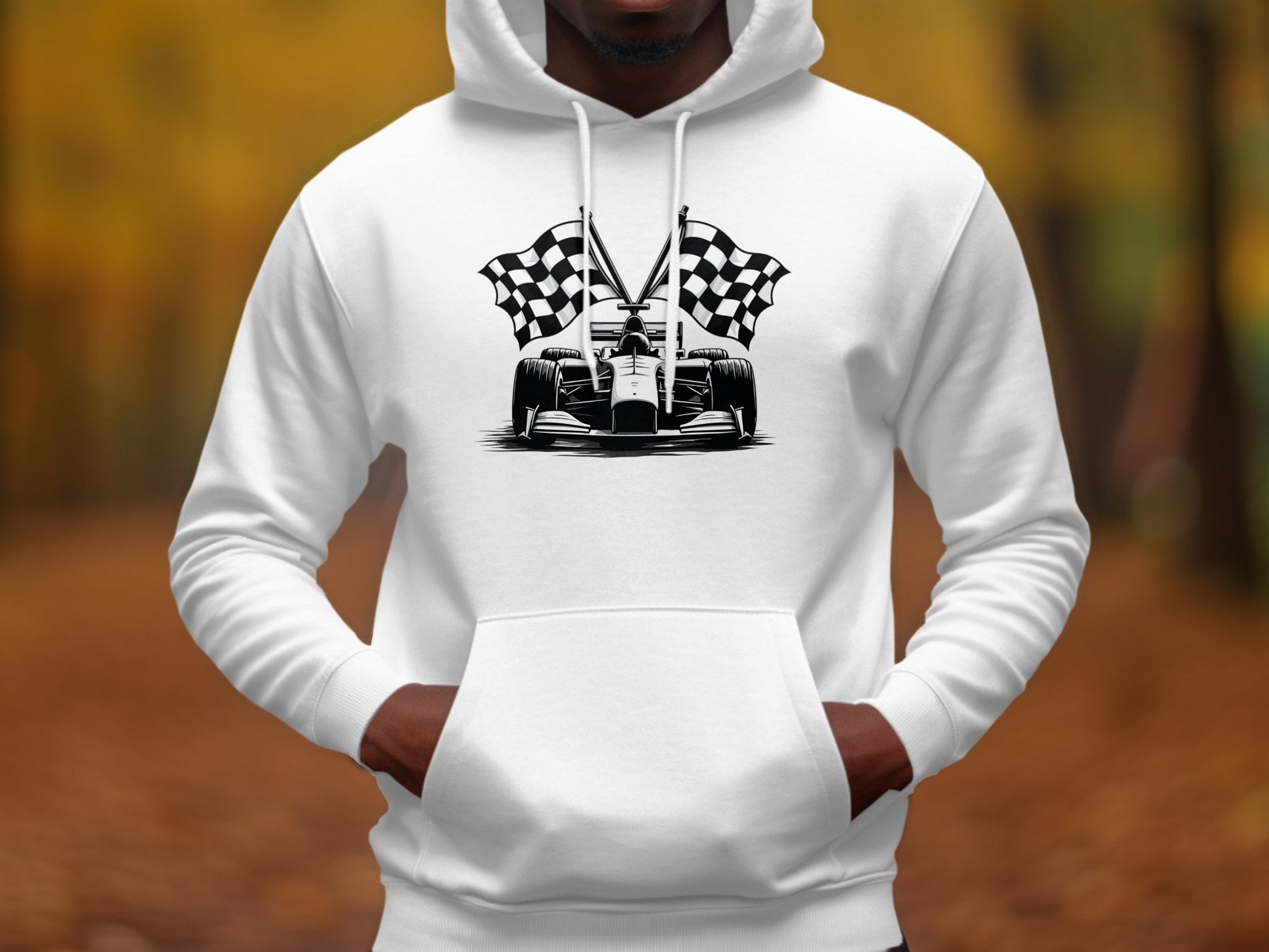 A person sports a Garment Graphics white hoodie showcasing a black and white race car with checkered flags. Ideal for motorsport fans, the backdrop is a blur of autumn colors and fallen leaves.