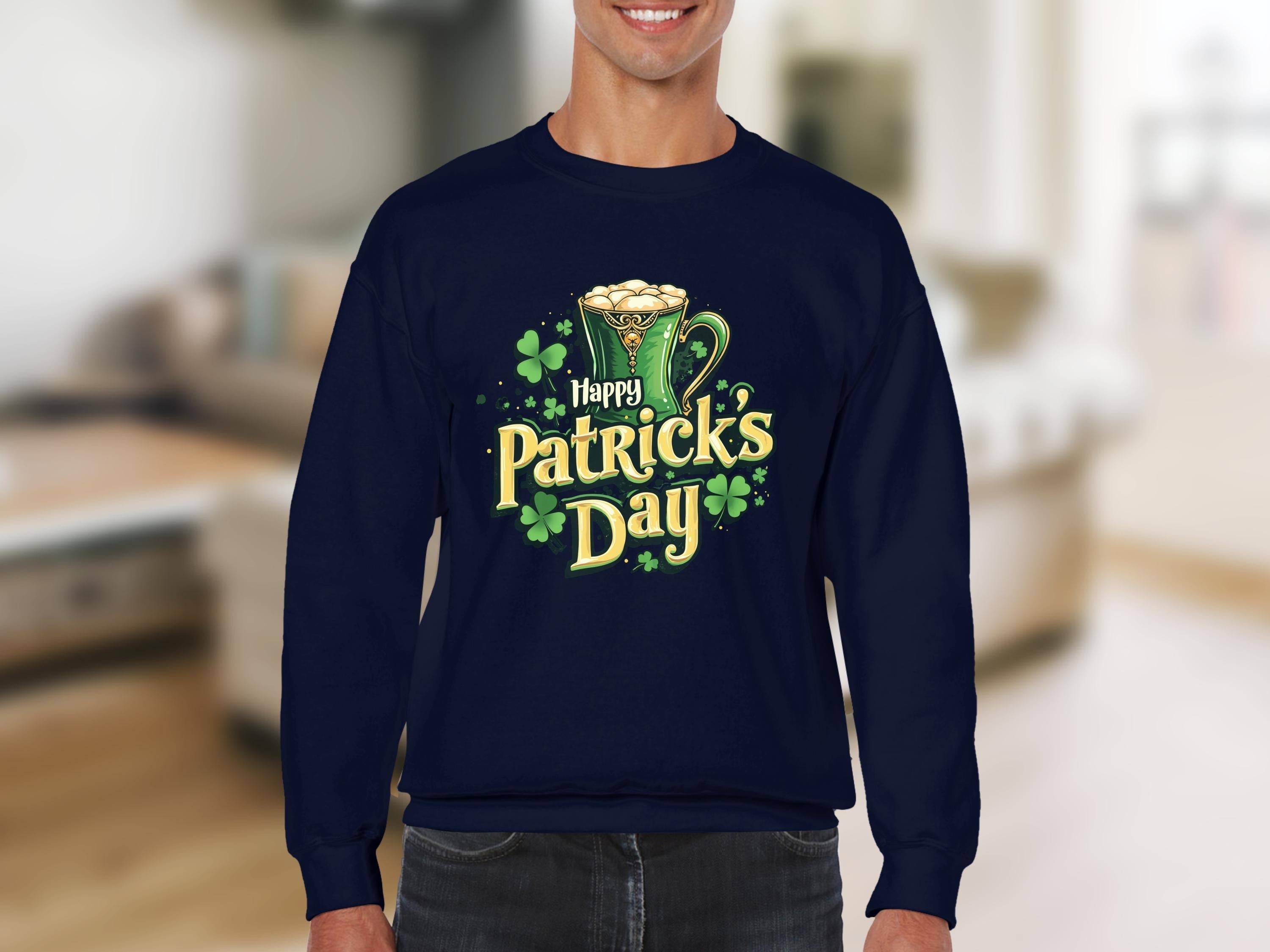 A person is in a blurry indoor setting, wearing a vibrant Happy Patricks Day sweatshirt from Garment Graphics, featuring a festive graphic with a cheerful mug of beer and clovers.