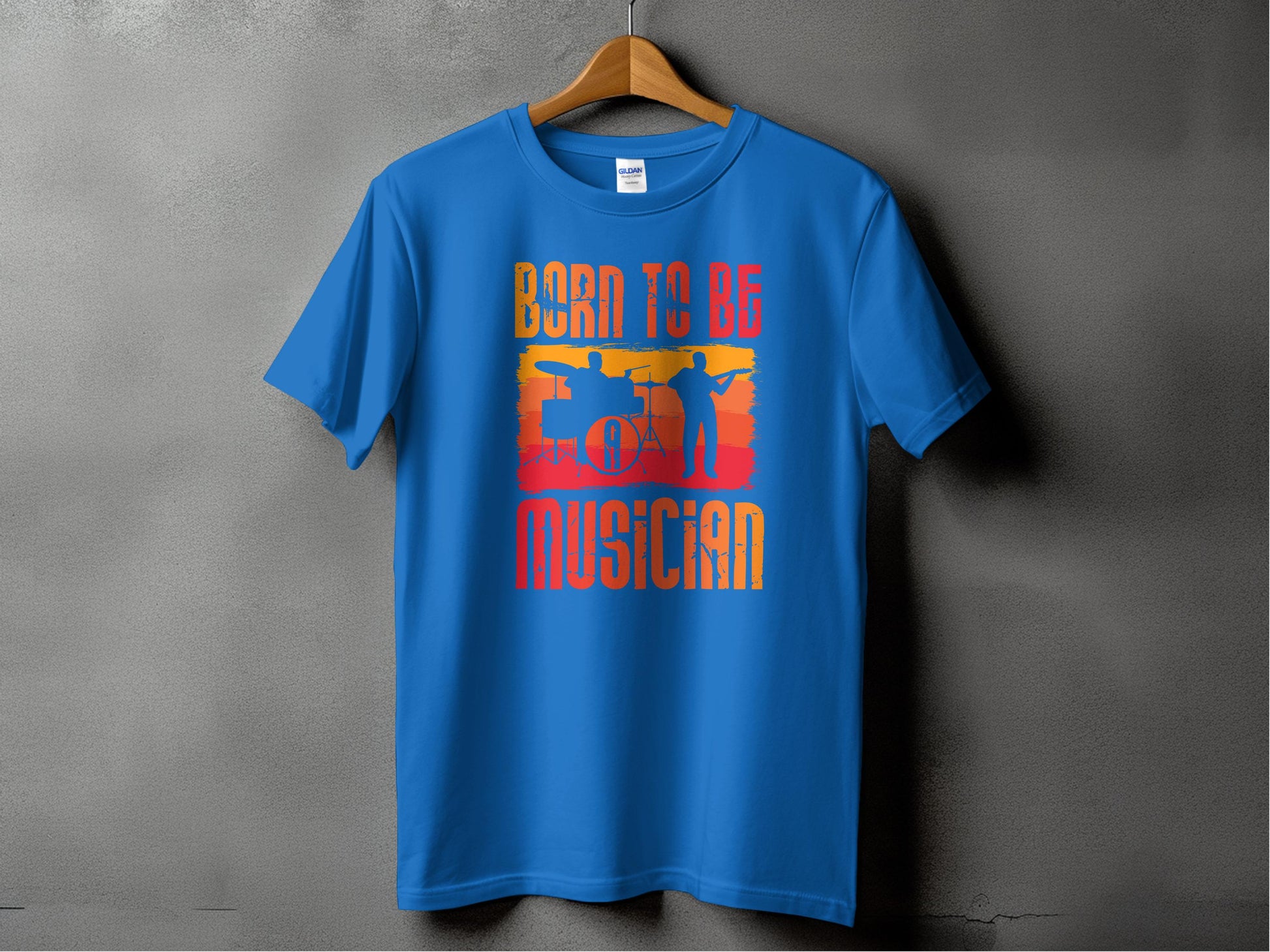 A Garment Graphics blue Born to be a Musician T-shirt, featuring bold text and silhouettes of a drummer and guitarist against a vibrant sunset design, hangs on a wooden hanger against a gray background—ideal for music lovers.
