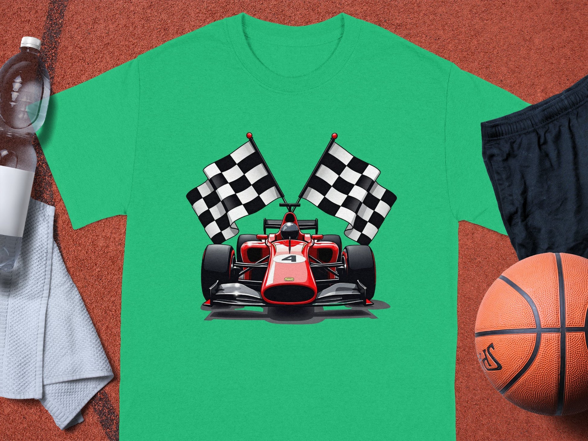 A green T-shirt from Garment Graphics features a stylish race car design with the number 4 and two checkered flags on a sports surface. Nearby items include a water bottle, towel, black shorts, and a basketball. Perfect for any motorsport enthusiast!.