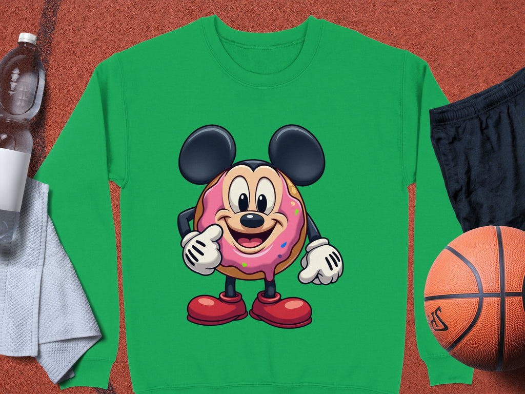 Garment Graphics fun staple, this green sweatshirt features a quirky cartoon character with big ears and red shoes, enjoying a donut. Styled on terracotta with essentials including a white towel, water bottle, black shorts, and basketball.