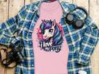 A whimsical pink T-shirt from Garment Graphics, ideal for unicorn lovers, features a unicorn graphic with I love my pony text. Its creatively displayed on wood alongside a blue and green flannel shirt, camera, headphones, and a coffee cup.