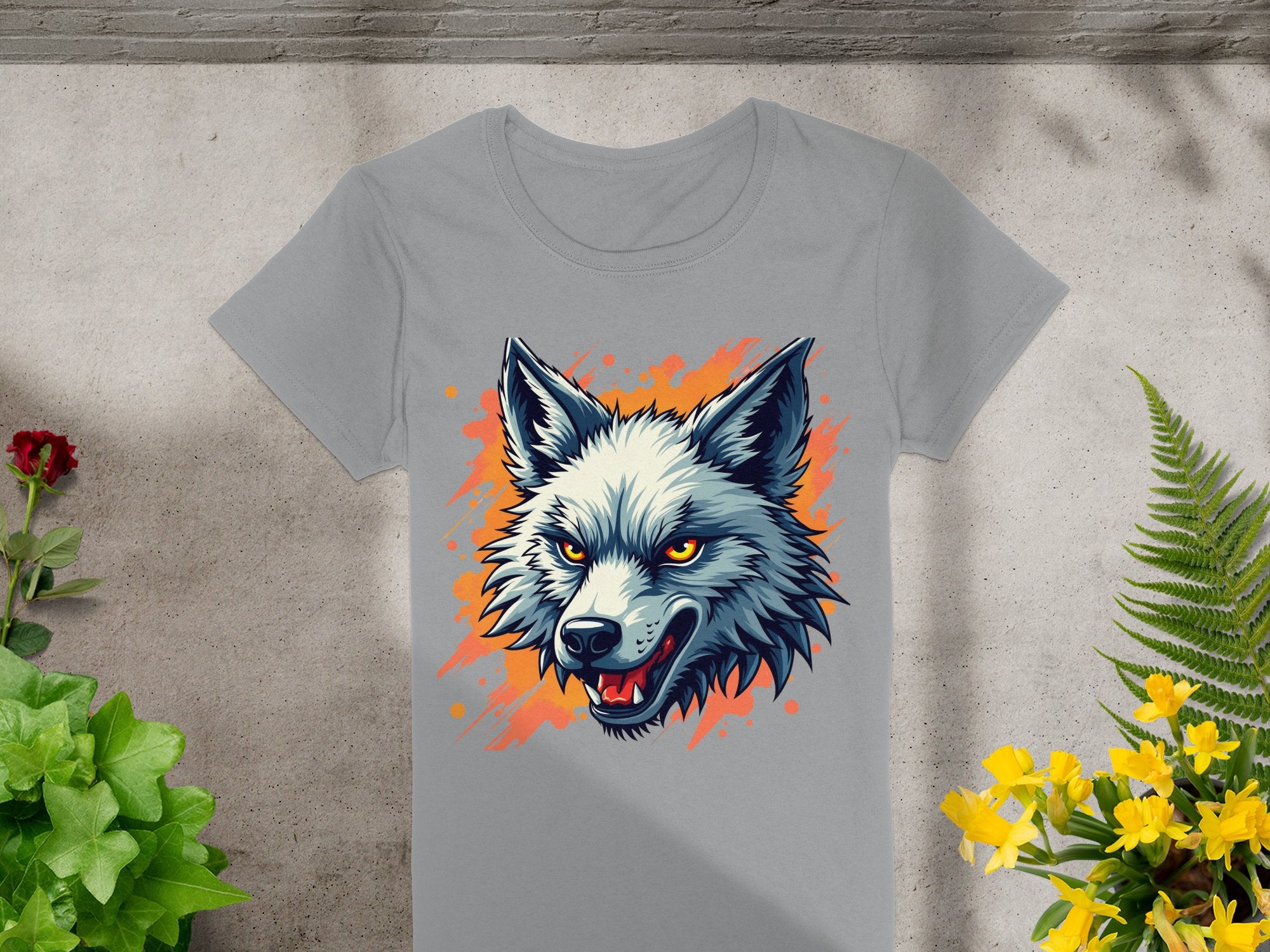 This Garment Graphics 100% cotton T-shirt features a bold gray wolf print with striking yellow eyes and an orange background. Surrounded by green plants and vivid red and yellow flowers, it showcases a daring personality when displayed on a concrete surface.