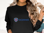 A person with long wavy hair is wearing a black Garment Graphics sweatshirt, featuring a blue text and red griffin emblem. This unisex Scania logo top is ideal for casual outings, though the persons face isnt visible.