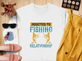 A white sweatshirt from Garment Graphics with unisex sizing displays Addicted to Fishing, Relationship and fish graphics. Its styled on a wooden surface with a mustard blazer, sunglasses, makeup brushes and palette, pink loafers, nail polish, and a pouch.