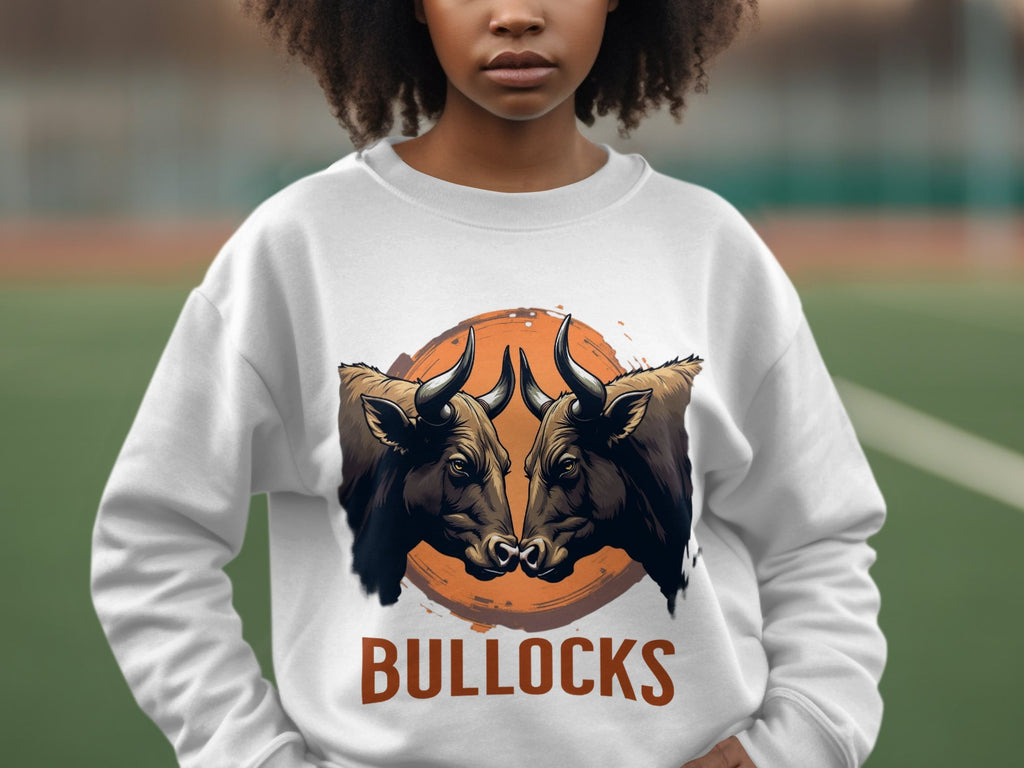 A person wears an eye-catching Garment Graphics sweatshirt featuring two bulls facing each other with BULLOCKS below, set against a blurred outdoor backdrop of green and brown tones, adding style with its loose fit.