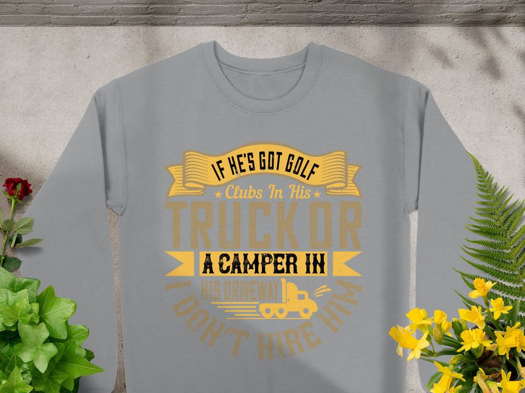 Garment Graphics gray t-shirt features the humorous text, If hes got golf clubs in his truck or a camper in his driveway, I dont hire him, in yellow and brown, surrounded by red and yellow flowers, adding a playful touch to your casual wear.