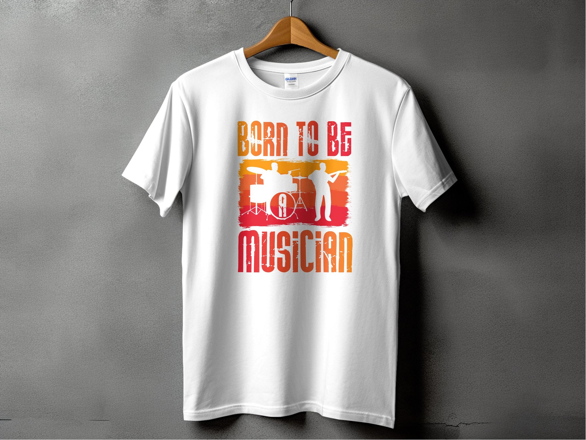 The Garment Graphics Born To Be Musician T-shirt hangs on a wooden hanger, perfect for music lovers. The white tee features the phrase in a red-orange gradient with silhouettes of a drummer against gray, ideal for passionate drummers or guitarists.