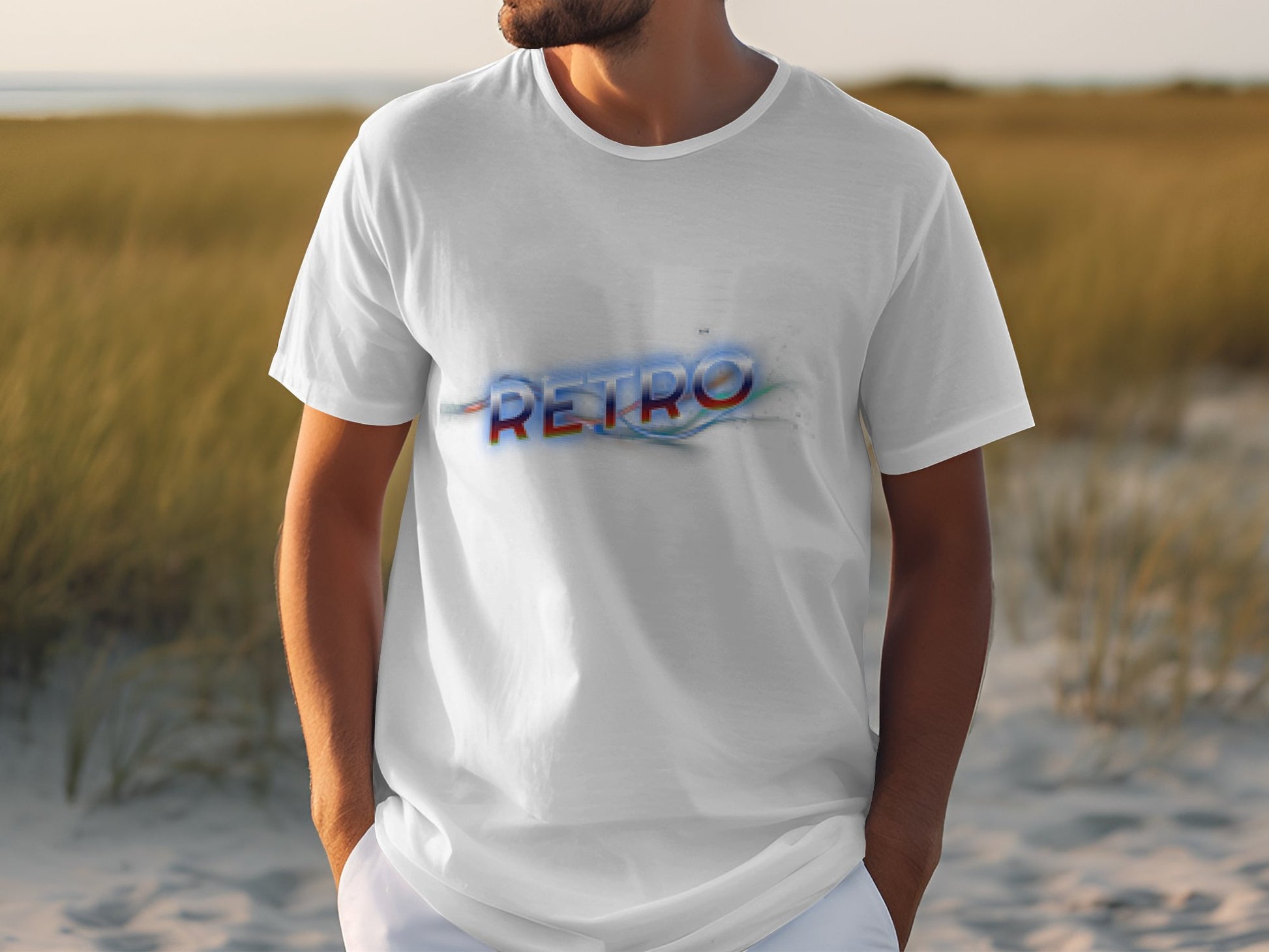 A man stands outdoors on grass in a classic-fit white T-shirt by Garment Graphics, featuring the word RETRO in colorful, distorted text. The background showcases more grass and a blurred horizon, enhancing the shirts vintage charm.