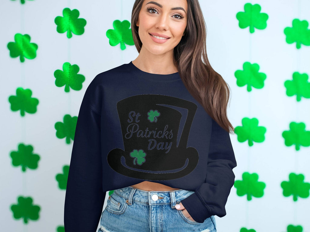 A woman exudes festive cheer in a Garment Graphics navy sweatshirt featuring a St Patricks Day leprechaun hat. Her long hair and smile shine against green shamrock patterns, perfectly paired with denim shorts.