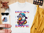 Garment Graphics offers a white t-shirt with a vibrant duck wearing glasses, a cap, and a scarf, accompanied by the bold text Ducks Dope. Style it effortlessly with sunglasses, makeup brushes, nail polish, pink shoes, and a yellow jacket for added flair.