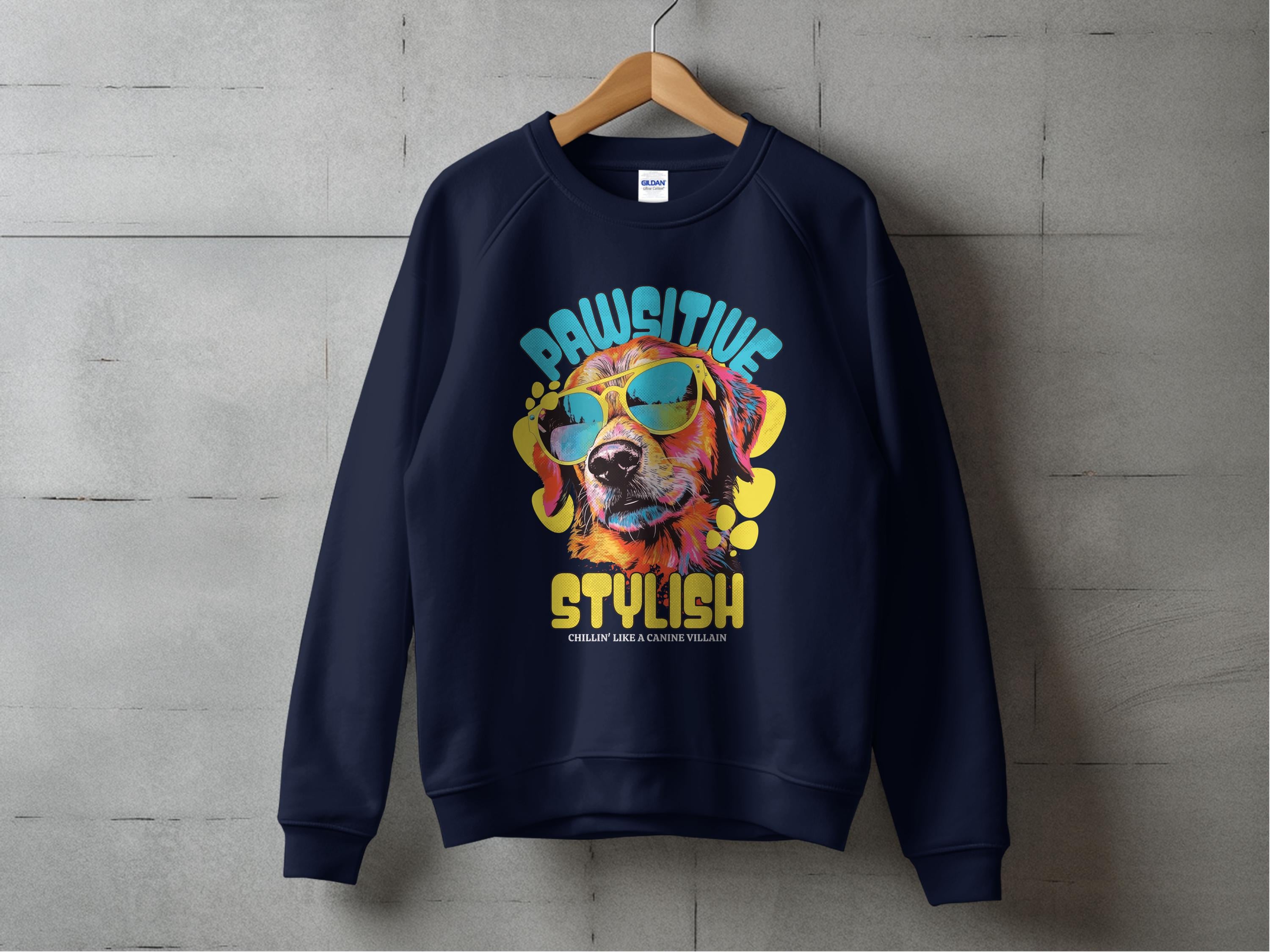 A navy blue sweatshirt by Garment Graphics hangs against a gray wall, showcasing a canine in sunglasses with the text Pawsitive Stylish and Celebrate Every Canine Walker, ideal for dog lovers who enjoy Dog Graphic Sweatshirts.