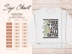 Next to a white Garment Graphics Gildan 18000 heavyweight crewneck sweatshirt featuring an alligator holding a basketball, with the text See you later alligator, theres a size chart with unisex measurements in inches.