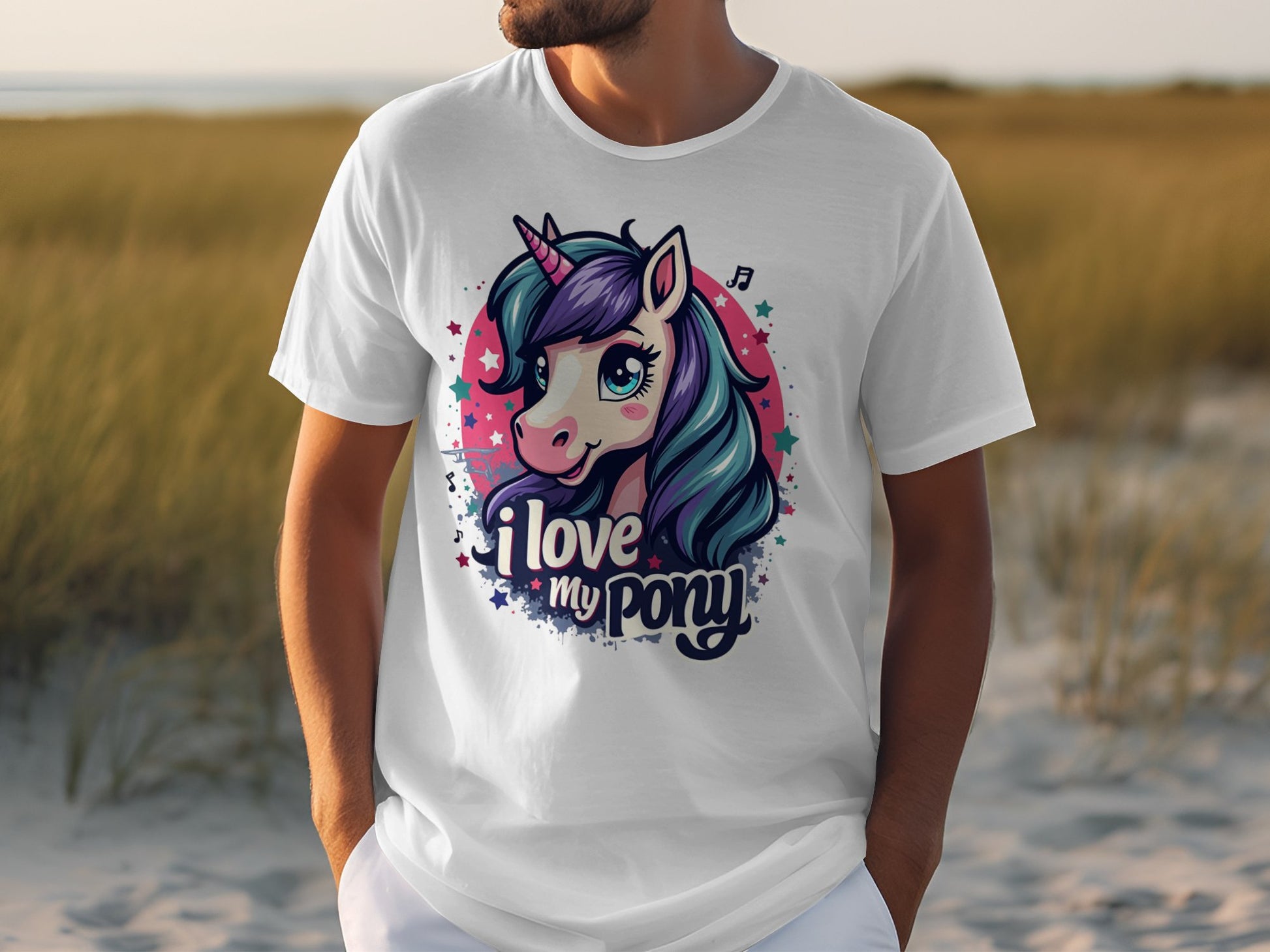 A unicorn enthusiast shows off their whimsical style on the beach wearing a Garment Graphics white Pony T-shirt adorned with a colorful unicorn with blue and purple hair. I love my pony dances among musical notes and stars, where grass meets sand.