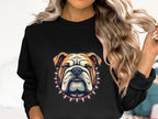 A woman with long, wavy hair wears a Garment Graphics black sweatshirt featuring a bulldog design with a spiked collar. Playfully holding her right-hand hair strand, the softly blurred background emphasizes the trendy unisex appeal of the sweatshirt.