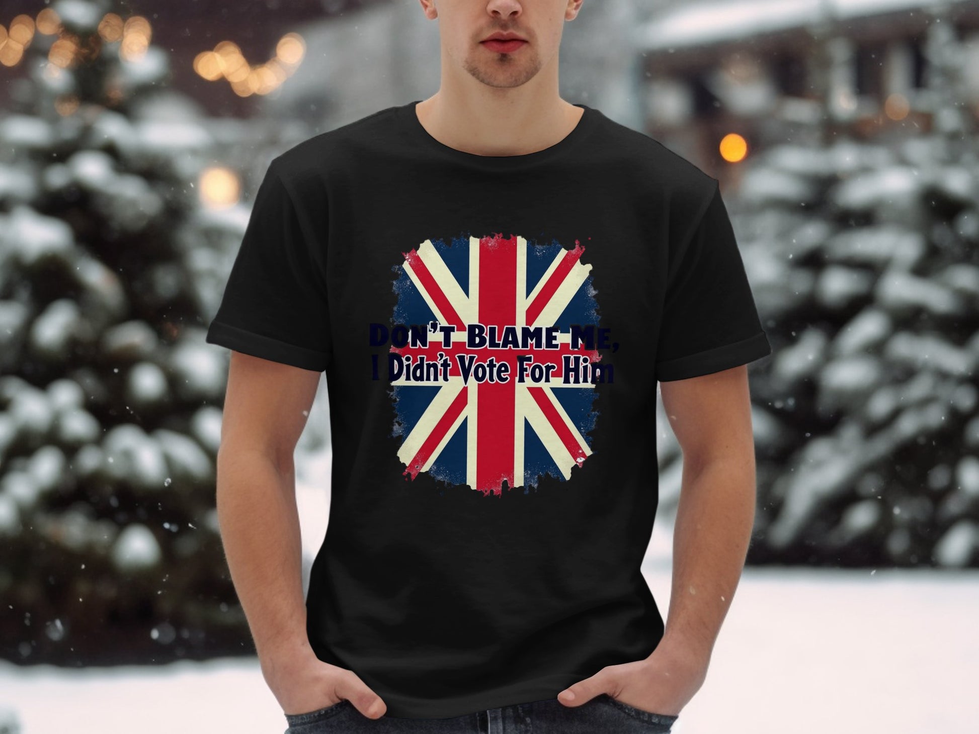 In a snowy scene with blurred lights, someone dons a Garment Graphics classic fit black T-shirt featuring a bold, distressed Union Jack design and the phrase DONT BLAME ME, I didnt Vote for Him.