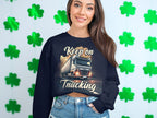 A person with long hair wears a black Keep On Trucking graphic sweatshirt by Garment Graphics, standing against a wall with green shamrock cutouts. The unisex sizing makes it ideal for those who enjoy a stylish, laid-back vibe.