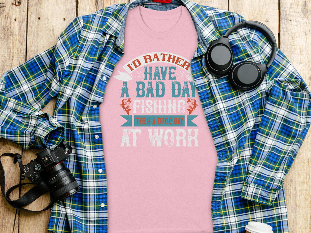 Garment Graphics plaid shirt over a fishing T-shirt with the text Id rather have a bad day fishing than a good day at work makes a great gift for anglers, styled next to a camera and headphones on wood.