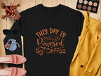 Flat lay of Garment Graphics graphic sweatshirt with This day is powered by coffee in brown, surrounded by makeup brushes, eyeshadow palette, sunglasses, lipstick, red nail polish, pink shoes, blue pouch, and mustard yellow blazer on wood—a playful design for coffee lovers.