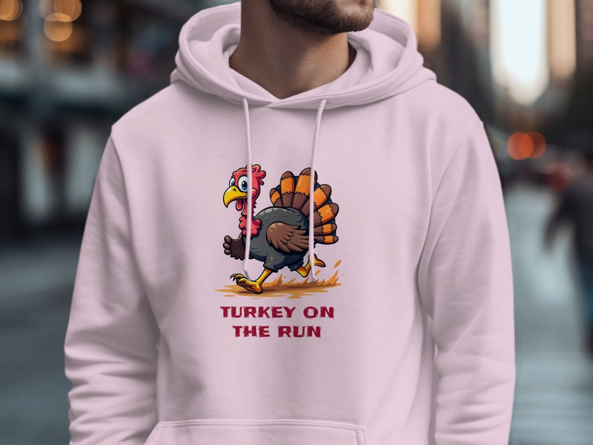 A person sports a Garment Graphics white hoodie featuring Turkey On The Run, showcasing a cartoon turkey. The fun design pops against the blurred urban street scene backdrop.