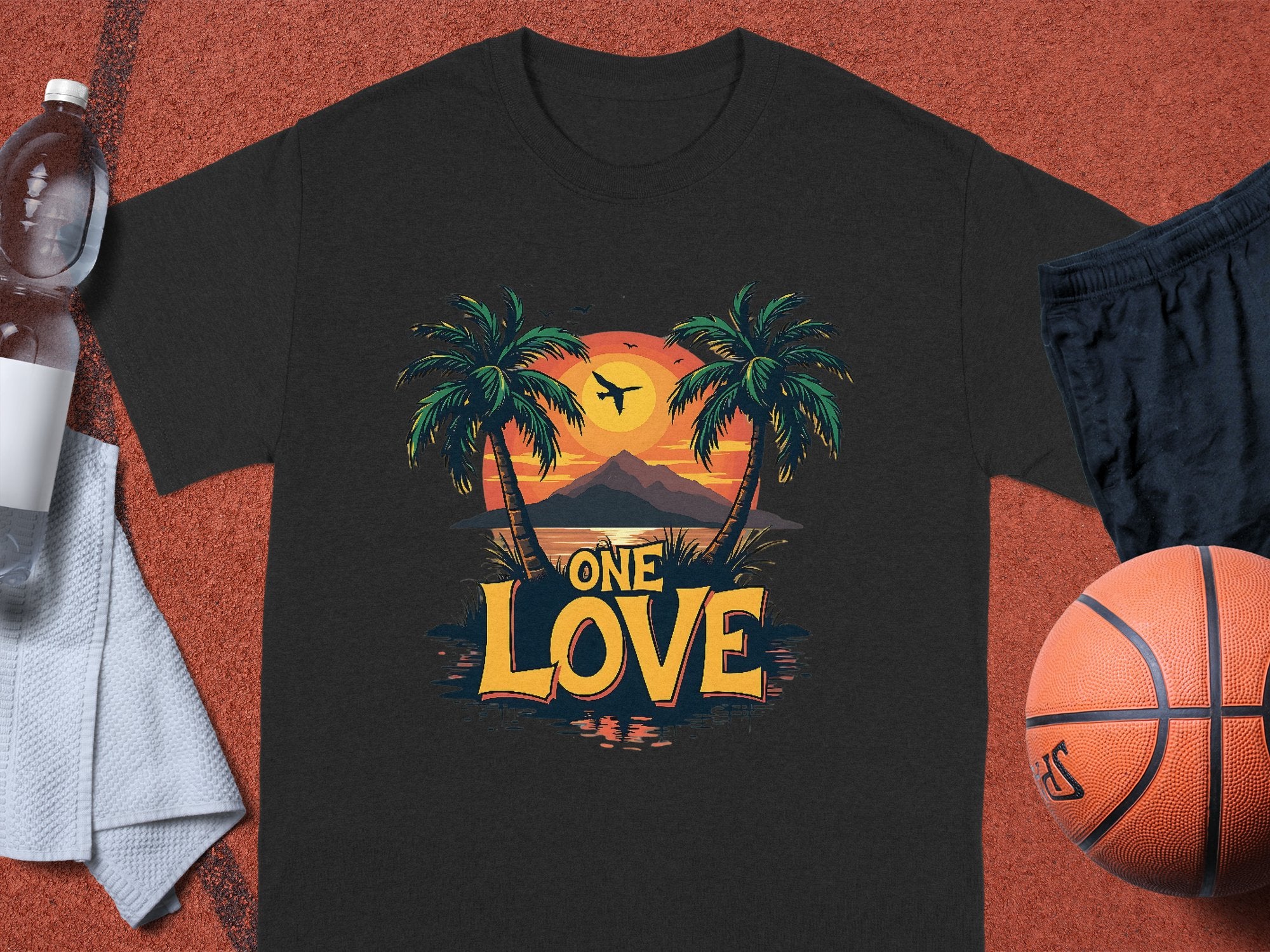 A Garment Graphics black cotton T-shirt features two palm trees, a tropical sunset with an airplane silhouette, and ONE LOVE in bold. Ideal for beach lovers, it’s styled with a water bottle, towel, shorts, and basketball.