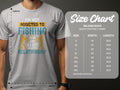 A person dons a gray Garment Graphics Fishing T-shirt reading Im not addicted to fishing, were just in a very committed relationship, with a Gildan 5000 heavy cotton T-shirt size chart from S to 5XL beside them, ideal for avid anglers.