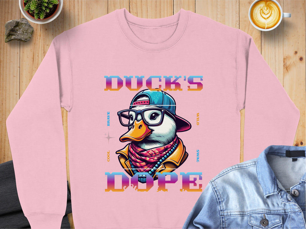 Garment Graphics offers a pink unisex sweatshirt with a cartoon duck in a cap, glasses, and scarf from the Brave Cool Swag collection. Made from medium-heavy fabric, it reads Ducks Dope and pairs stylishly with coffee, stones, and denim shirts for everyone’s comfort.