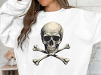 A person wears Garment Graphics unisex white sweatshirt featuring an edgy skull and crossbones on the front, with long, wavy hair partially out of frame.