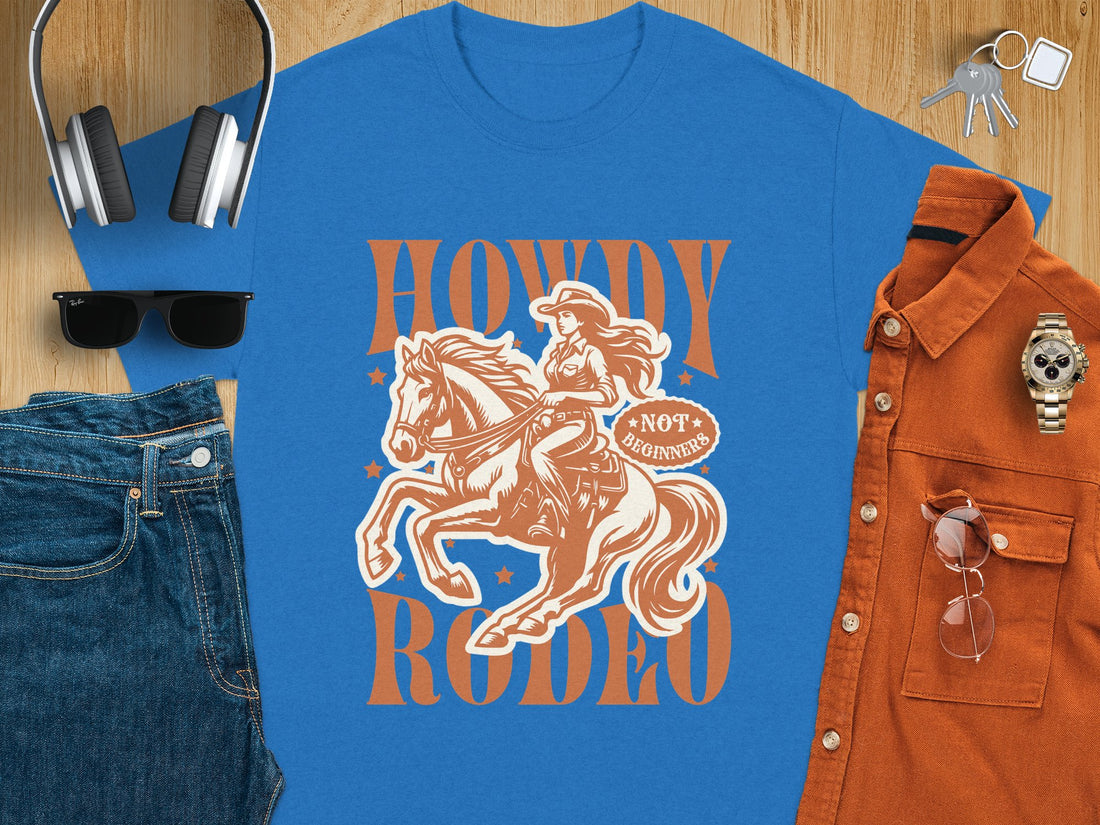 A person is wearing a white Garment Graphics T-Shirt featuring a brown cowboy on a horse with the text Howdy Rodeo and Not Branded. The background of grass and sand suggests a beach or dune, ideal for western culture fans.