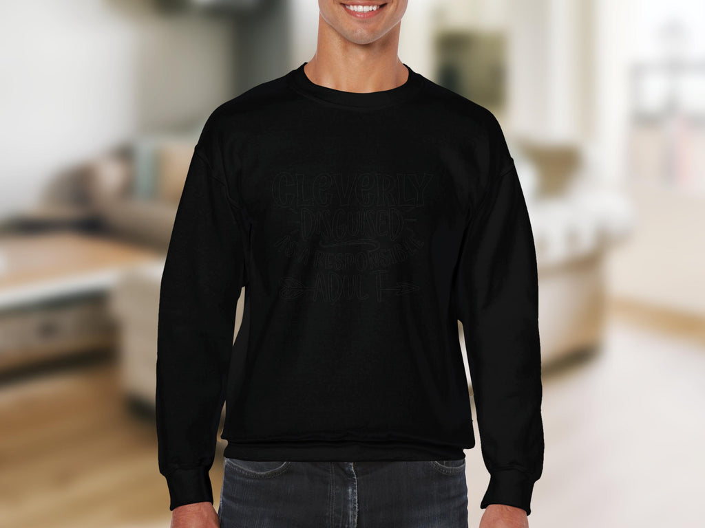 A person wears a black Garment Graphics sweatshirt with dark lettering indoors. The blurred living room background with light furnishings highlights its unisex sizings versatility in a curated humor wardrobe.