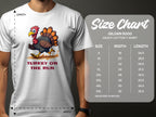 A person wears a Garment Graphics white t-shirt with a cartoon turkey and Turkey On The Run text. This funny tee comes in family sizes S to 5XL, featuring a size chart with Gildan 5000 heavy cotton t-shirt dimensions for width and length.