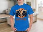 A person wears a blue Classic Fit T-shirt by Garment Graphics, featuring two bulls facing each other inside an orange circle and the word BULLOCKS below. The blurred interior background highlights stylish simplicity ideal for fans of Bullocks Pintable T-Shirts.