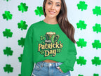 A person wearing a vibrant St. Patricks Day sweater by Garment Graphics, featuring a festive beer mug and shamrocks, stands before a wall adorned with green shamrocks. With long hair flowing and denim shorts completing the look, they effortlessly embody the holiday spirit.