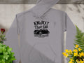 Garment Graphics gray vintage car hoodie features Enjoy Classic Car and Vintage Ride Community Since 1980 in black, along with a retro car design. Perfect for embracing community spirit among vibrantly colored potted plants on a textured surface, it blends style and nostalgia effortlessly.